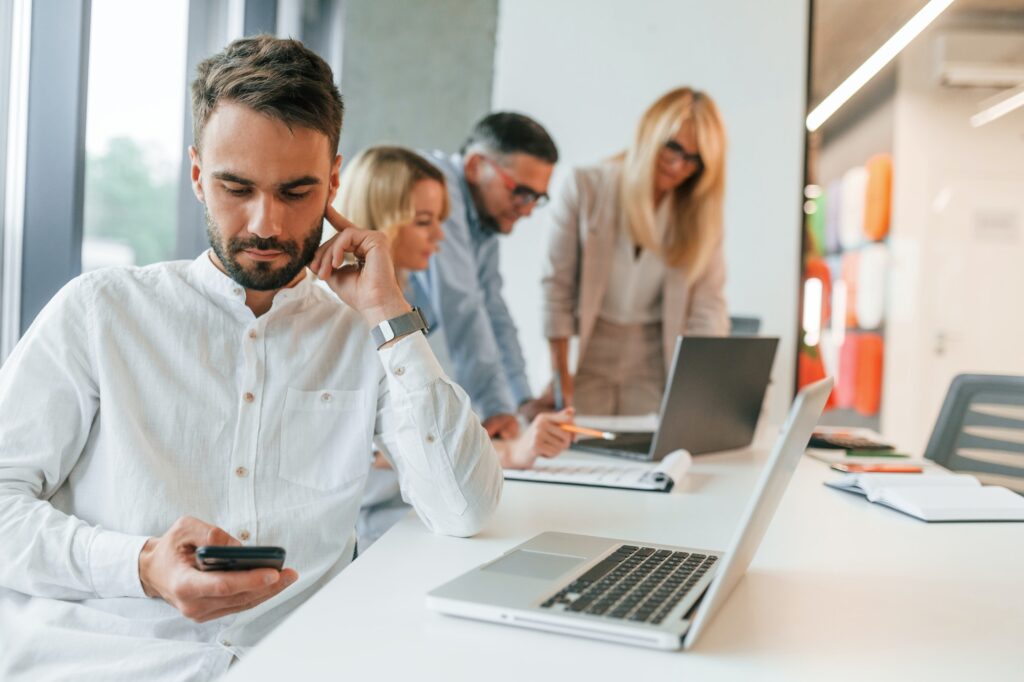 Young stylish man is working. Group of professional business people is in the office